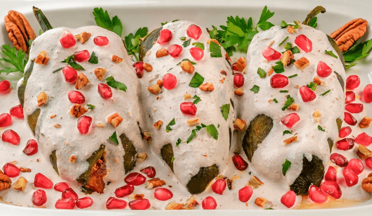 Chile poblano bañado en nogada (salsa blanca), con perejil verde y granada roja.