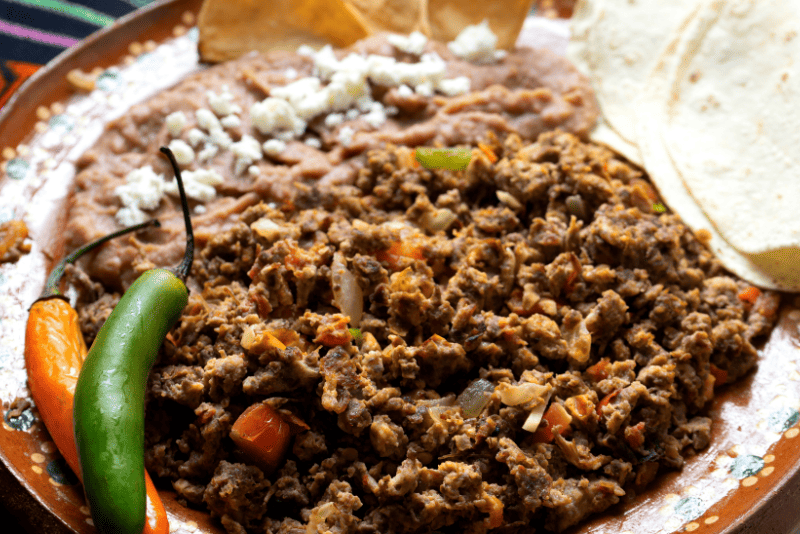 Plato de machaca con huevo revuelto, servido con tortillas calientes.