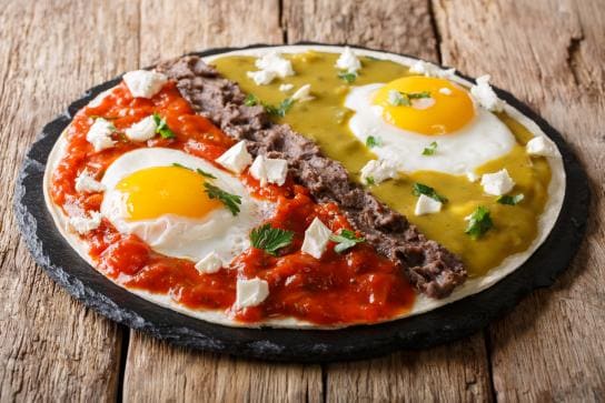 Plato de huevos divorciados, con salsa roja y salsa verde claramente separadas por frijoles.